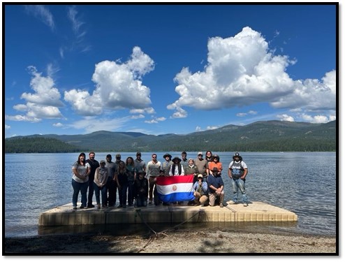 Group photograph with Peruvian flag on a mountain lake dock.